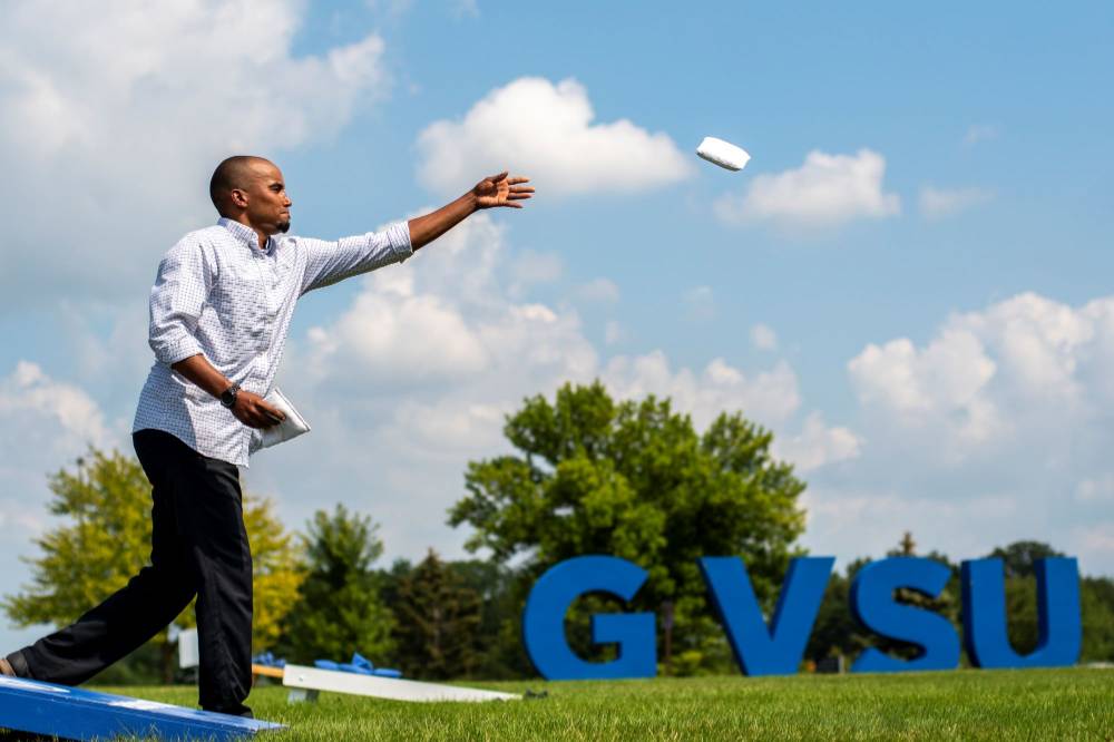 Taylor Boyd throws a bag with the GVSU letters in the background